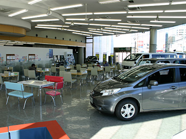 店内はとっても広く、大きな窓からはたくさんの光が降りそそいでいます。ゆったりとしたレイアウトで、色々な角度からお気に入りのお車や、気になる一台をご覧いただけます。