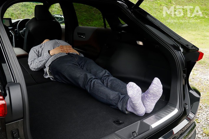 トヨタ 新型ハリアー ラゲッジ（荷室）での車中泊（イメージ）／荷室長は1805ｍｍ（トヨタ社内測定値）だが、実際には後席シート背もたれよりも頭が上に出てしまい浮いている状態。このままでは寝ることが出来ない。[モデルの身長180cm]