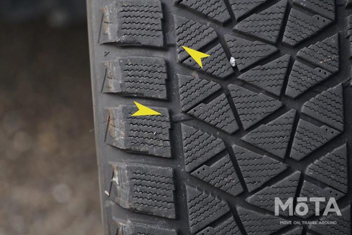 矢印で指している2箇所のサインは、夏用冬用問わず設置されているタイや摩耗限界を示すスリップサインだ。スタッドレスタイヤの場合、性能を発揮するために溝が深いこともあるが、スリップサインが露出するまで使用することはやめた方が良い。