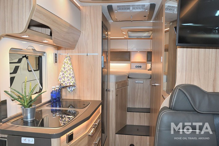 左はシンクやガスコンロ、レンジや冷蔵庫が揃い、右扉奥にはシャワー兼トイレ、そして大きなベッドルームが備わる