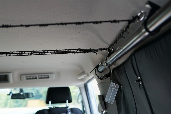 金属のパイプとゴムひもを組み合わせた天井収納。就寝時にスマホやマスクを引っ掛ける